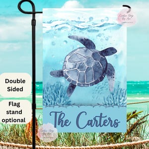 May include: A blue watercolor sea turtle with the text "The Carters" on a light blue background. The image is a garden flag with a double-sided design.