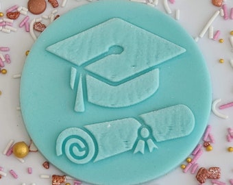 May include: A light blue circular graduation-themed decoration featuring a mortarboard and diploma design. The decoration is surrounded by colorful sprinkles in shades of pink, white, and gold. This item is suitable for cakes and cupcakes.