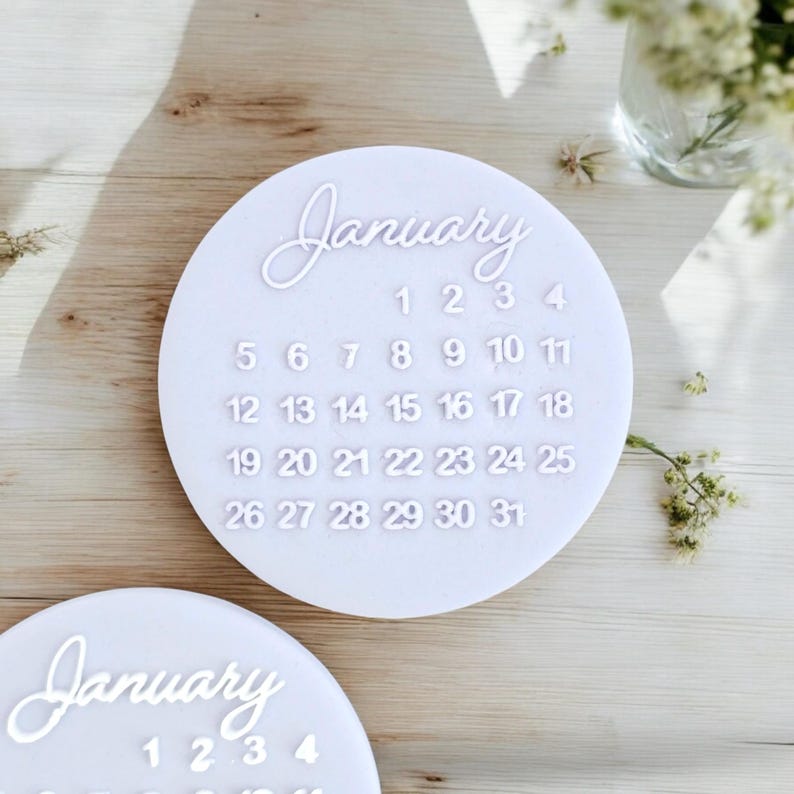 May include: White circular calendar with the month of January and the numbers 1 through 31. The calendar is on a wooden surface.