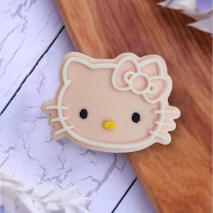 May include: A pink Hello Kitty cookie with white icing and a yellow nose.
