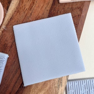 May include: A light blue silicone baking mat with a textured diamond pattern. The mat is designed for use in the kitchen for baking and rolling out dough.