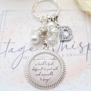 May include: Silver keychain with a charm that reads "An amazing coworker is hard to find, difficult to part with and impossible to forget". The charm is surrounded by white and clear beads and a silver letter D.