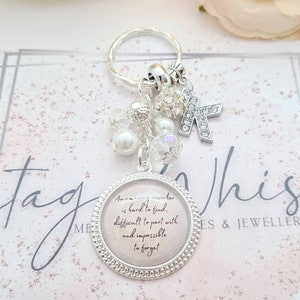 May include: Silver keychain with a charm that reads "An amazing coworker is hard to find, difficult to part with and impossible to forget". The charm is surrounded by small silver beads and a silver letter K.