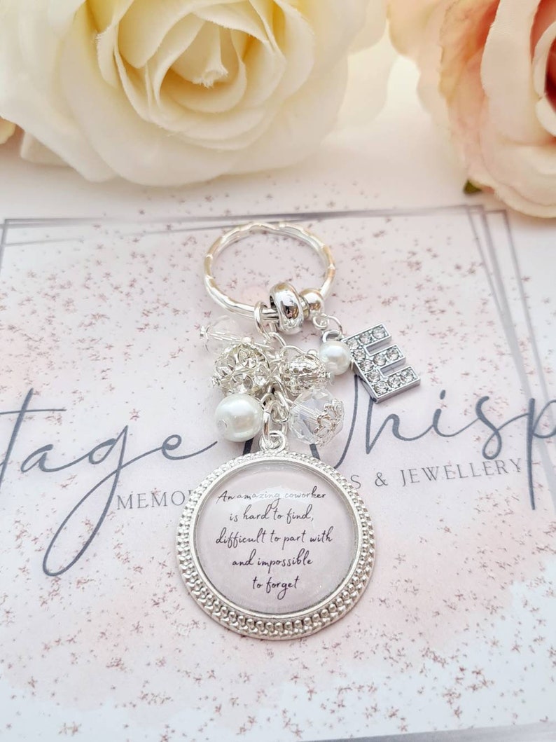 May include: A silver keychain with a charm that reads "Amazing coworkers are hard to find, difficult to part with and impossible to forget". The charm is surrounded by small silver beads and a pearl.
