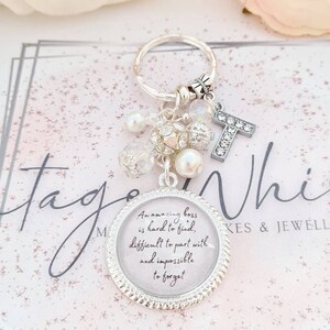 May include: A silver keychain with a charm that says "An amazing boss is hard to find, difficult to part with and impossible to forget". The charm is surrounded by small white beads and a silver letter T.