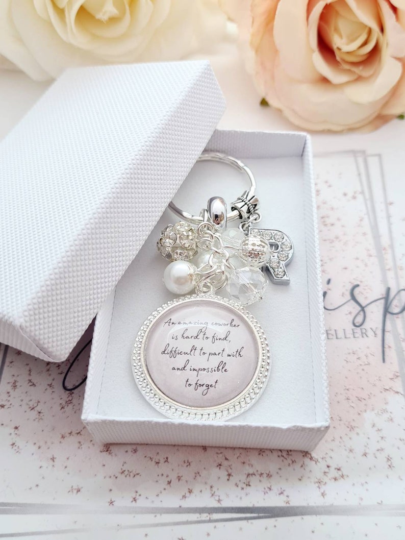 May include: A silver keychain with a charm that reads "An amazing coworker is hard to find, difficult to part with and impossible to forget". The charm is surrounded by small silver beads and crystals.