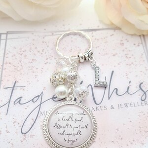 May include: A silver keychain with a charm that reads "An amazing coworker is hard to find, difficult to part with and impossible to forget". The charm is surrounded by white and clear beads.