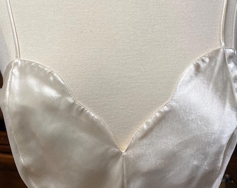 May include: A white satin slip dress with a sweetheart neckline and thin straps.