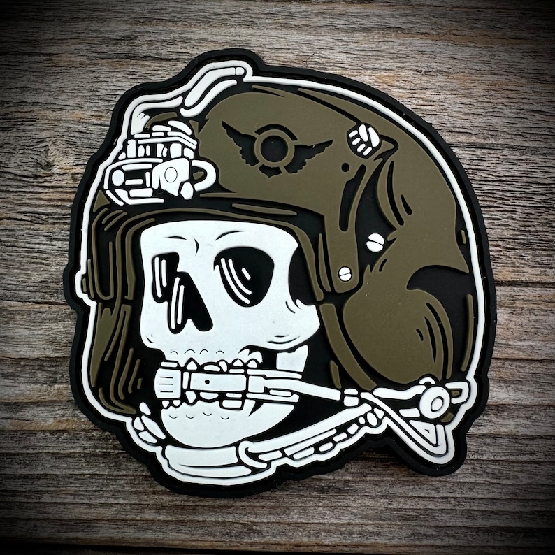 May include: A white skull wearing a green military helmet with a white skull and crossbones emblem. The helmet has a white strap and a white oxygen mask.