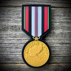 May include: A black and gold embroidered patch with the text "Afghanistan Campaign" and a map of Afghanistan. The patch is shaped like a medal with a ribbon.