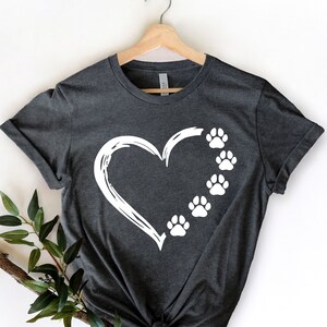 May include: A dark gray t-shirt with a white heart and paw prints design. The heart is outlined in white and has five paw prints inside.