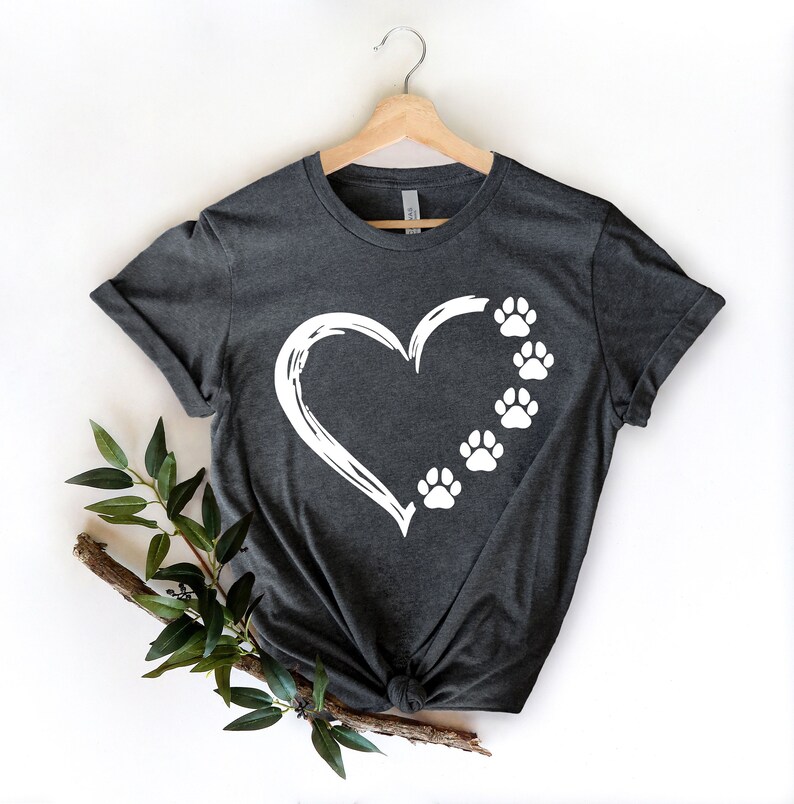 May include: A dark gray t-shirt with a white heart and paw prints design. The heart is outlined in white and has five paw prints inside.