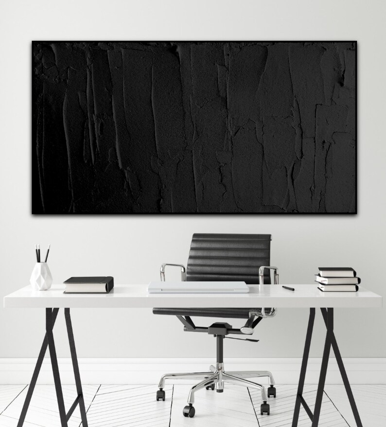 Puede incluir: Un espacio de oficina en blanco y negro con una pintura abstracta texturizada negra colgada en la pared sobre un escritorio blanco con una silla de oficina negra.