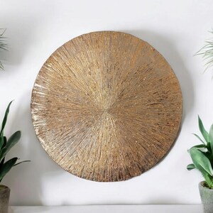 May include: A round, gold-toned wall decor with a textured, sunburst design.