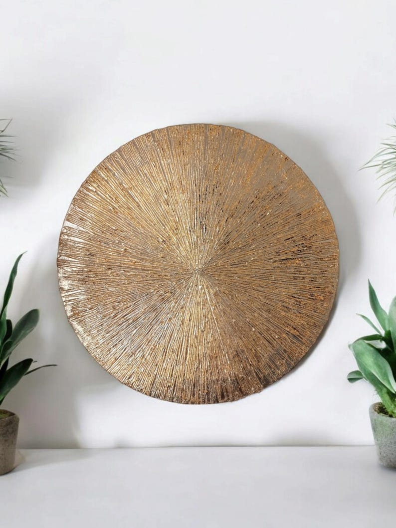 May include: A round, gold-toned wall decor with a textured, sunburst design.
