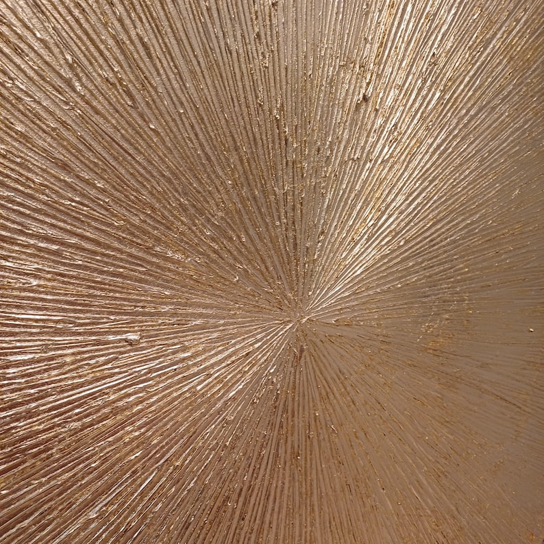 May include: A close-up of a textured, metallic gold surface with a radial pattern. The surface is smooth and shiny, with a subtle shimmer.