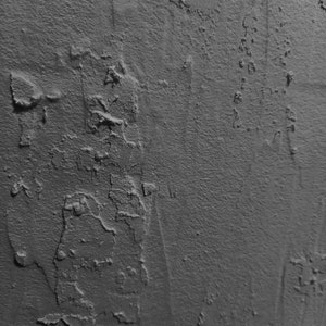 Peut inclure: Gros plan sur un mur textur&eacute; gris avec une surface rugueuse et irr&eacute;guli&egrave;re. Le mur a un aspect vieilli, avec des zones de peinture &eacute;caill&eacute;e et des fissures.