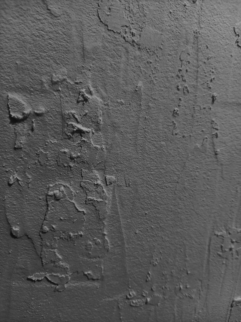 Peut inclure: Gros plan sur un mur textur&eacute; gris avec une surface rugueuse et irr&eacute;guli&egrave;re. Le mur a un aspect vieilli, avec des zones de peinture &eacute;caill&eacute;e et des fissures.