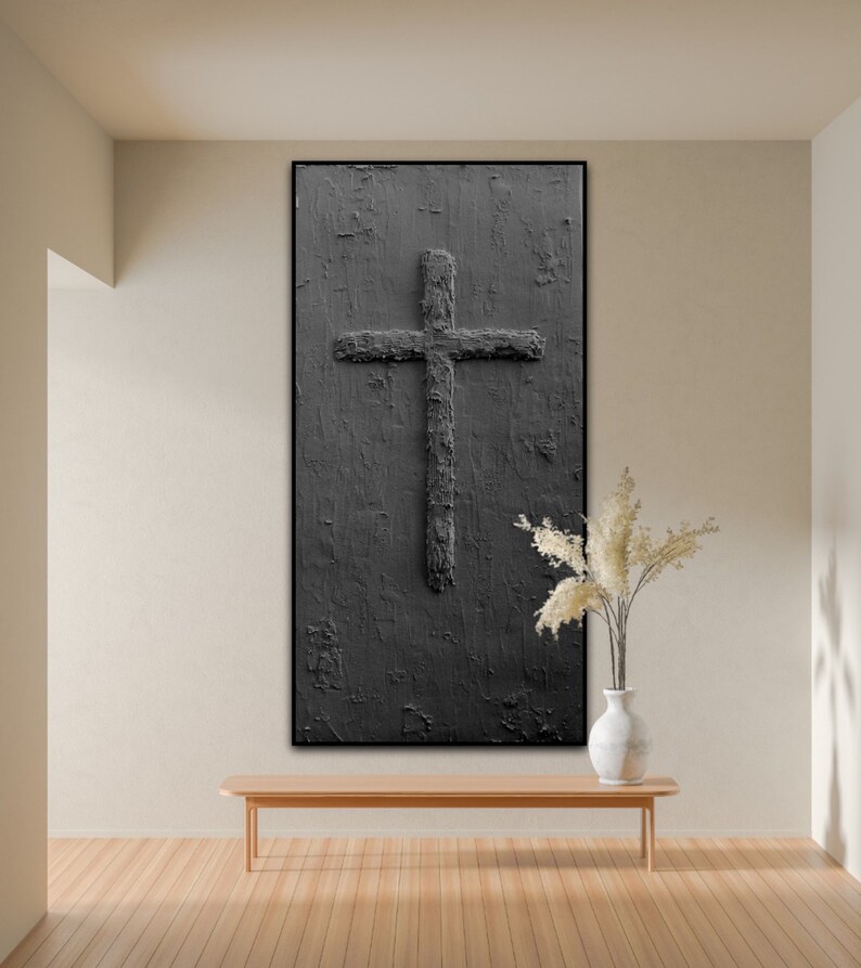 Peut inclure: Une peinture abstraite en noir et blanc d'une croix sur un fond textur&eacute;. La peinture est encadr&eacute;e en noir et est accroch&eacute;e &agrave; un mur beige au-dessus d'un banc en bois.