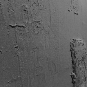 Peut inclure: Gros plan sur un mur gris textur&eacute; avec une surface rugueuse et irr&eacute;guli&egrave;re. Le mur pr&eacute;sente un motif vertical avec des zones plus textur&eacute;es que d'autres.