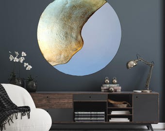 May include: A circular abstract wall art piece with a gold and blue color scheme. The gold paint is textured and appears to be dripping down the side of the circle. The blue paint is smooth and covers the bottom half of the circle.