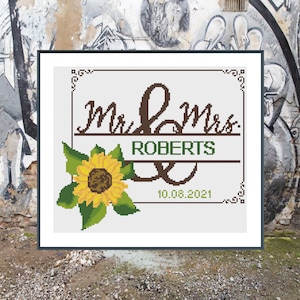 May include: A cross-stitch pattern with a sunflower and the text "Mr & Mrs Roberts 10.08.2021".