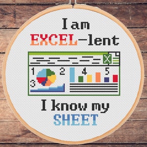 以下が含まれることがあります： 「私はEXCEL-lentです。シートを知っています」と書かれた白い刺繍枠のクロスステッチデザイン。デザインには、円グラフ、棒グラフ、数字が描かれたスタイリッシュなスプレッドシートが含まれています。
