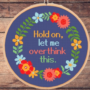 May include: A blue embroidery hoop with a floral wreath and the text "Hold on, let me overthink this."