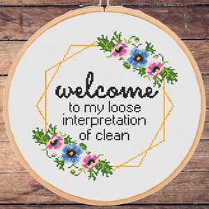 Könnte beinhalten: Ein weißer Stickrahmen mit einem Blumendesign und dem Text "welcome to my loose interpretation of clean".