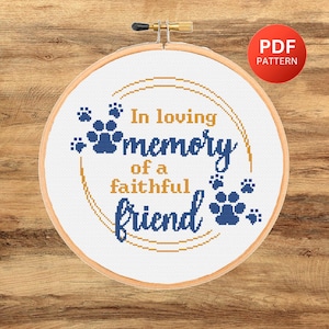 May include: A cross-stitch embroidery hoop with the words "In loving memory of a faithful friend" in blue and gold. The design includes paw prints and a PDF pattern label.