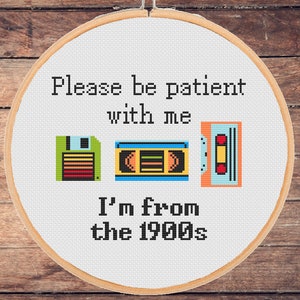May include: Cross-stitch hoop art with the text "Please be patient with me, I'm from the 1900s." The design includes pixelated images of a floppy disk, VHS tape, and cassette tape, all in bright colors.