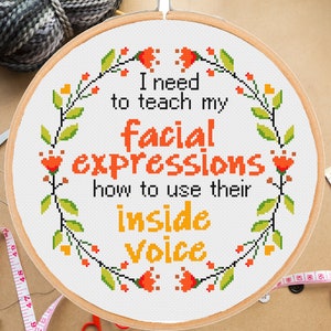 Puede incluir: Un aro de bordado blanco con un borde de corona floral. El aro presenta un diseño de punto de cruz con el texto "Necesito enseñarle a mis expresiones faciales cómo usar su voz interior."