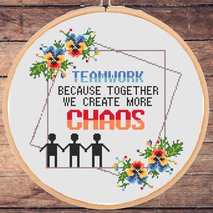 Puede incluir: Un aro de bordado blanco con un diseño de punto de cruz que presenta el texto "Teamwork because together we create more chaos" con cuatro figuras de palo tomadas de la mano y acentos florales.
