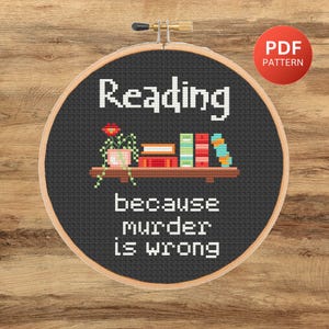 May include: Black and white cross stitch pattern with the text "Reading because murder is wrong". The pattern features a bookshelf with books and a potted plant.