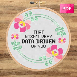 May include: Cross-stitch embroidery in a wooden hoop. The design features the text "THAT WASN'T VERY DATA DRIVEN OF YOU" in black, surrounded by pink flowers and green vines. A pink "PDF" label is in the upper right corner.