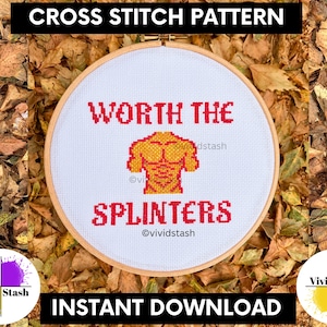 May include: A circular wooden embroidery hoop containing white Aida fabric with a cross stitch design. The design features the red text WORTH THE SPLINTERS and a yellow and orange muscular torso graphic in the center of the fabric.