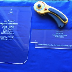 May include: Two clear acrylic sewing pattern templates with instructions for a beginner purse pattern. The templates are labeled "A" and "Sew Powerful Beginner Purse Pattern". The text on the templates includes instructions for cutting fabric, lining, and interfacing. The templates are 10 1/4 inches high and 7 1/2 inches wide.