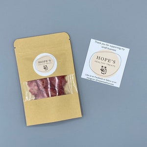 May include: A kraft paper bag with a clear window containing dried, reddish-brown treats. The bag has a circular label with the text "HOPE'S HEALTHY TREATS" and a small illustration. A card next to the bag reads "Thank you for supporting my small business."