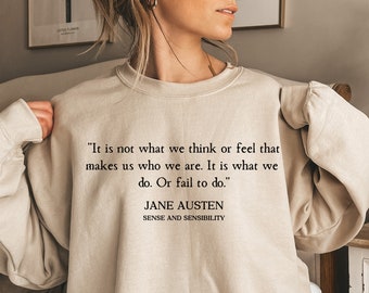 May include: A beige sweatshirt with a quote from Jane Austen's Sense and Sensibility: "It is not what we think or feel that makes us who we are. It is what we do. Or fail to do."