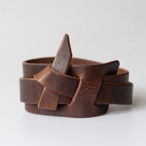 May include: A brown leather bracelet with a knotted design.