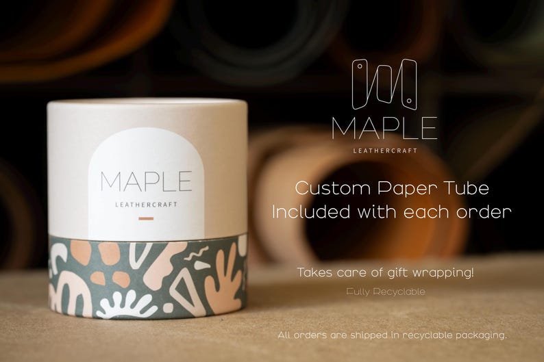Op de afbeelding: Een cilindrische papieren koker met een beige bovengedeelte met de tekst MAPLE LEATHERCRAFT in een witte boog. Het onderste gedeelte toont een donkergroen patroon met abstracte vormen in wit en perzik. De koker is recyclebaar.