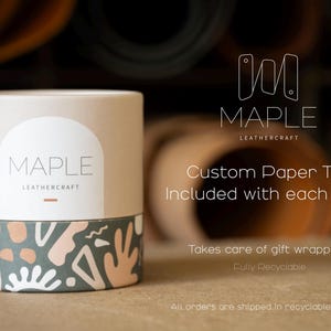 K&ouml;nnte beinhalten: Eine zylindrische Papierrolle mit hellbeiger Oberseite und dunkelgr&uuml;ner Basis, die ein abstraktes Muster in Wei&szlig;, Beige und Dunkelgr&uuml;n aufweist. Die Rolle zeigt den Text MAPLE LEATHERCRAFT, Custom Paper Tube Included with each order, Takes care of gift wrapping!, Fully Recyclable und All orders are shipped in recyclable packaging.