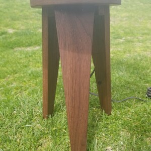 May include: A dark brown wooden table lamp base with a round top and three legs. The base is made of solid wood and has a natural finish.