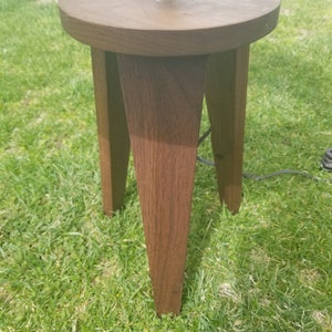 May include: A dark brown wooden lamp base with a round top and three legs. The base is made of solid wood and has a natural finish.