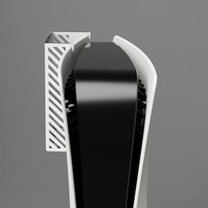 Könnte beinhalten: Eine weiße Spielekonsole mit einem schwarzen Lüftungsschlitz und einem weißen Plastikständer an der Seite. Die Konsole hat ein elegantes, modernes Design.
