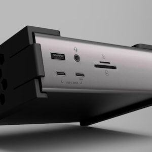 K&ouml;nnte beinhalten: Ein silbernes und schwarzes Computergeh&auml;use mit mehreren Anschl&uuml;ssen und einem wabenf&ouml;rmigen L&uuml;fter. Das Geh&auml;use hat ein schlankes, modernes Design mit dem Wort "Chopova" auf der Seite.