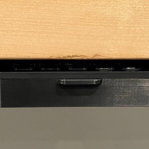 May include: A black under-desk drawer with a handle and a wood top.