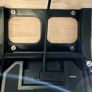 May include: A black 3D printed bracket with two rectangular cutouts, mounted to a wooden surface. A black cable is connected to a black device with the text "SOLID" and "1000 Type C" visible.