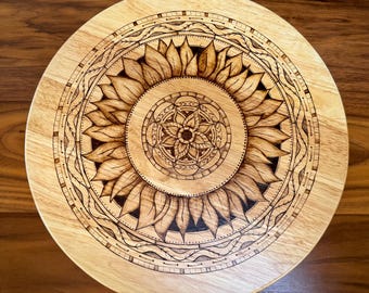 May include: A wooden serving tray with a woodburned design of a sunflower mandala. The sunflower has a detailed center with intricate patterns.