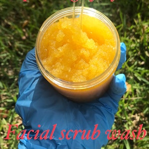 May include: A close-up of a glass jar filled with a yellow facial scrub. The jar is being held by a gloved hand. The text "@pdcdesignsforyou" and "Facial scrub wash" are visible in the image.